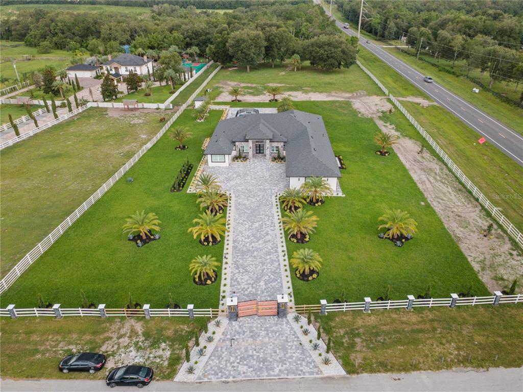 An aerial view shows a house with a paved driveway, gated entrance, and landscaped lawn — 34435 DONNA VISTA PLACE, EUSTIS, FL