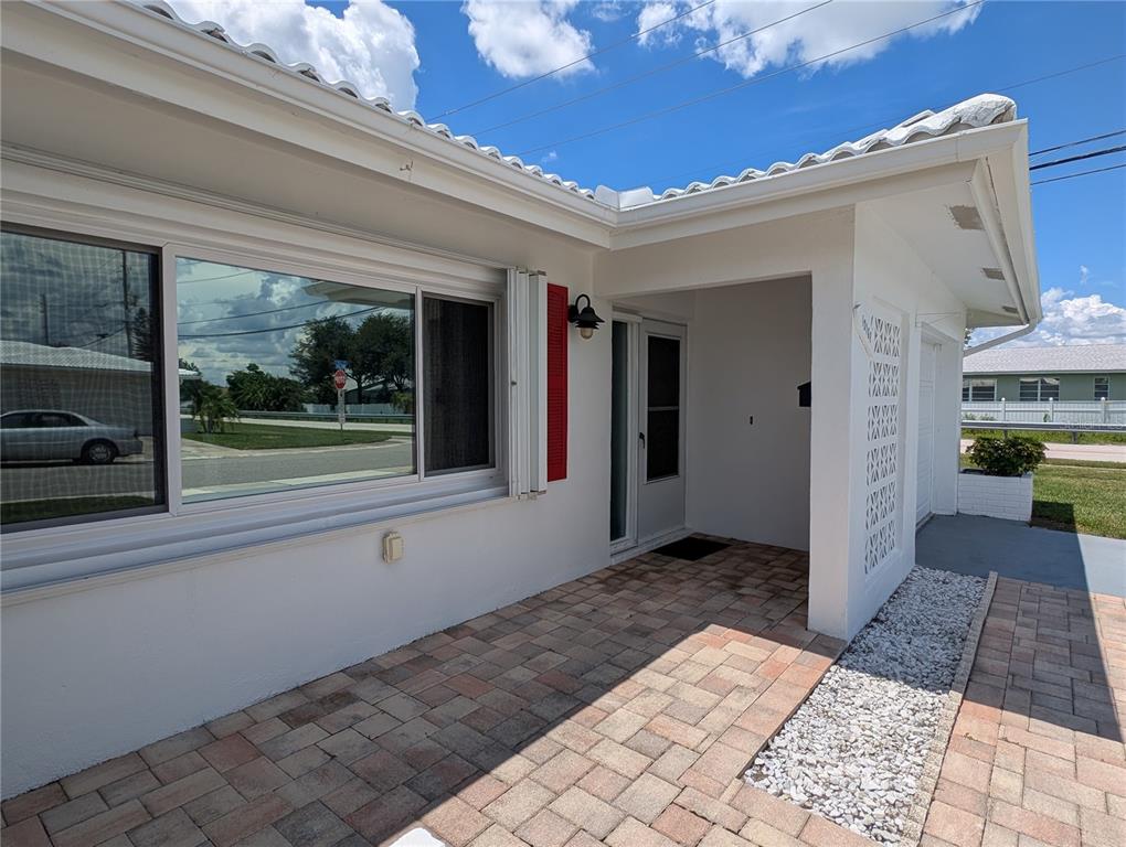 A white house exterior features a brick-paved patio, a large window, and a covered entryway — 10188 45TH STREET N UNIT 2, PINELLAS PARK, FL