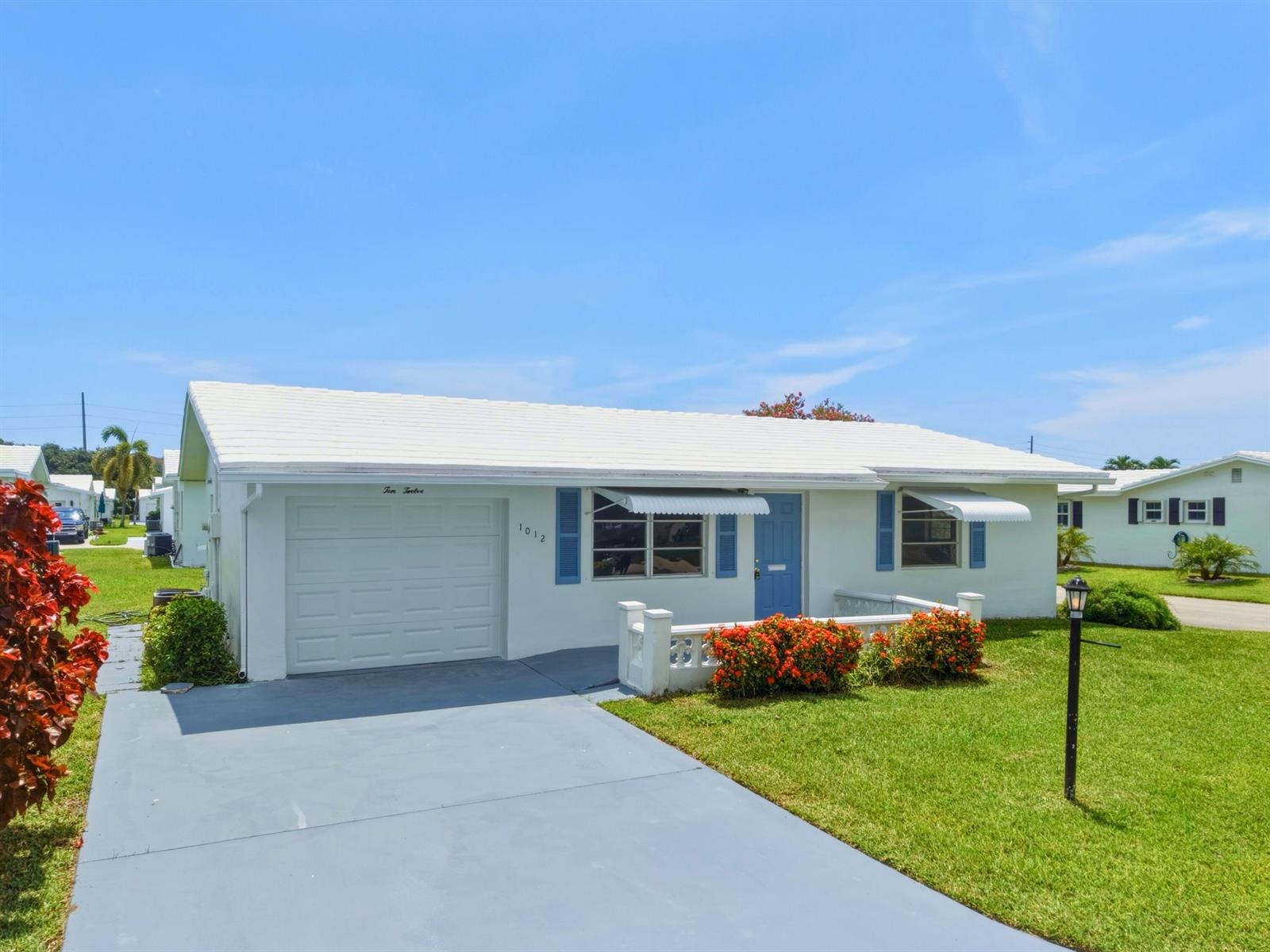 A single-story white house with a blue door, a garage, and a small front lawn — 1012 SW 17th Street, Boynton Beach FL 33426, BOYNTON BEACH, FL