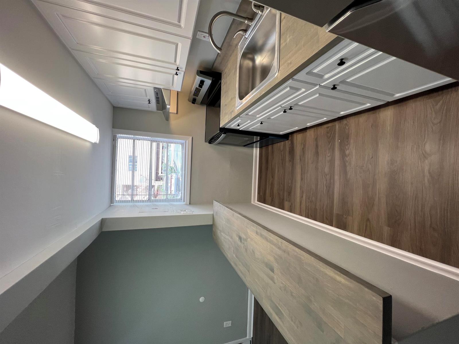 A kitchen features white cabinets, wood-look countertops, a stainless steel sink, and wood-style flooring — 2561 NW 135th Street # 3, Opa-Locka FL 33167, OPA-LOCKA, FL