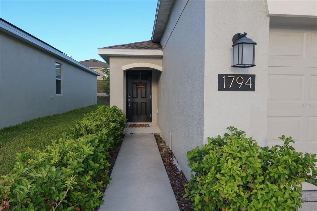 A concrete walkway leads to the front door of a house with a garage — 1794 PERCH HAMMOCK LOOP, GROVELAND, FL