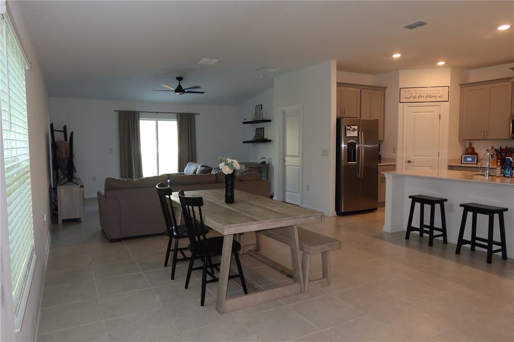 An open-concept living and dining area features tile flooring, a kitchen island, and neutral walls — 1794 PERCH HAMMOCK LOOP, GROVELAND, FL