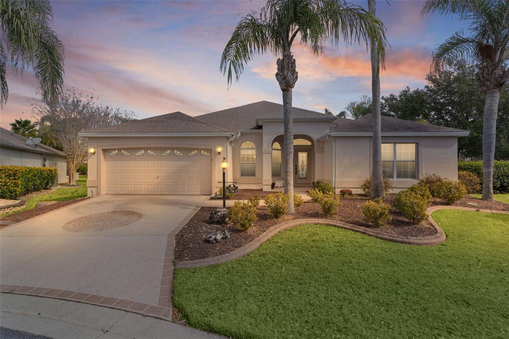 A single-story house with a two-car garage, palm trees, and a landscaped front yard — 758 MOORE TERRACE, THE VILLAGES, FL
