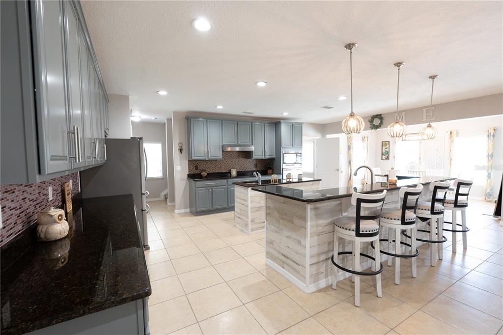 A covered patio features wicker furniture, a ceiling fan, a wall-mounted television, and a grill — 493 HOLLOW GLEN DRIVE, TITUSVILLE, FL