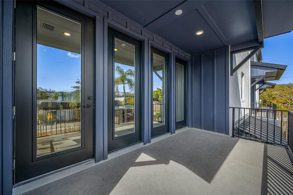 A covered balcony features dark blue walls, concrete flooring, and three black-framed glass doors — 3009 1ST AVENUE N, ST PETERSBURG, FL
