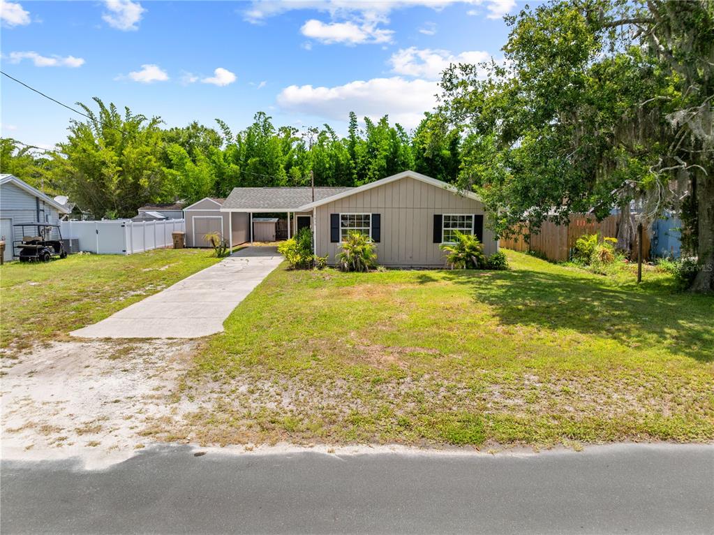 A single-story house with a carport, concrete driveway, and a large front yard — 1839 BURTON DRIVE, ST CLOUD, FL