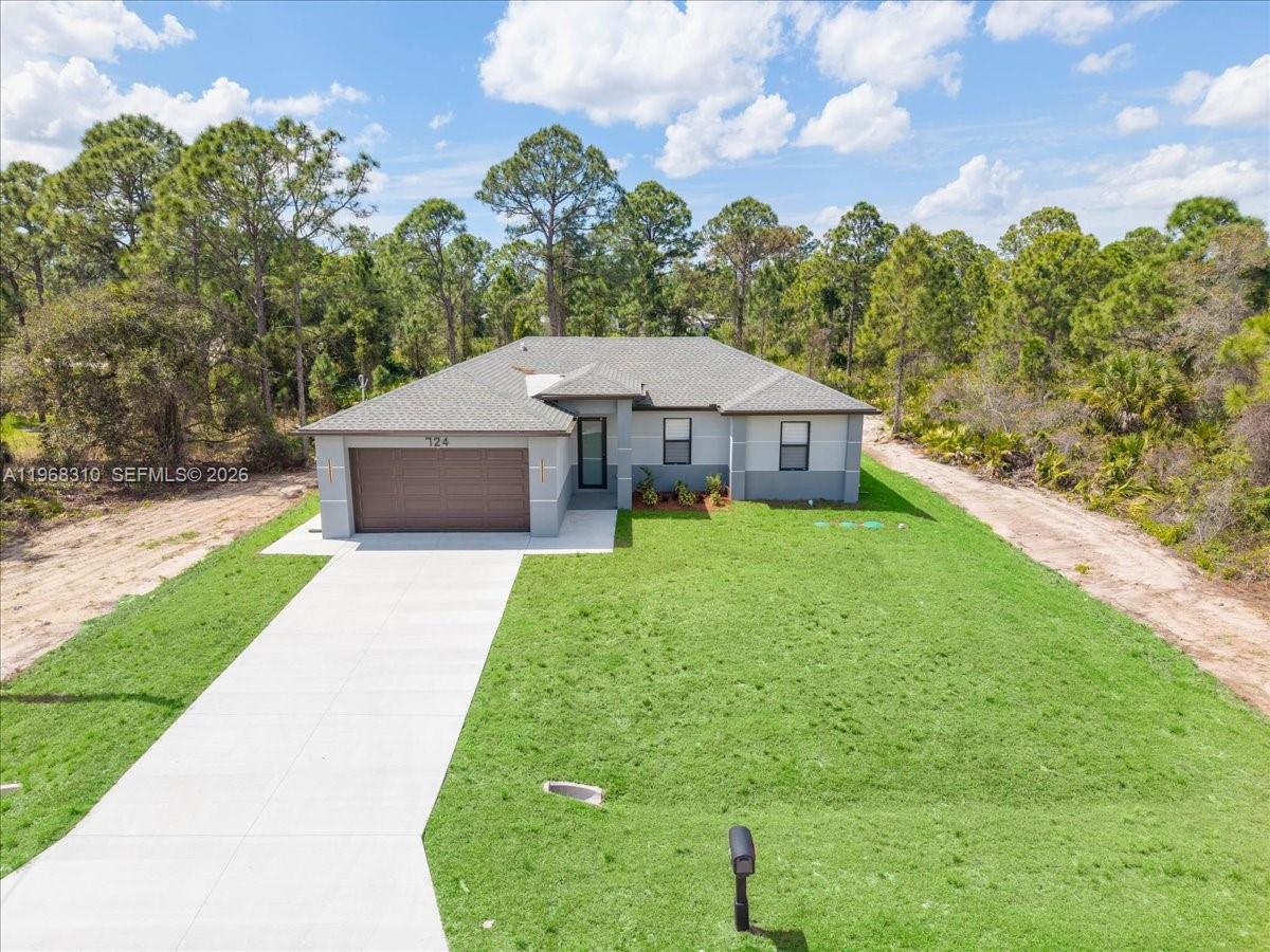 A single-story house with a gray exterior, a two-car garage, and a concrete driveway — 724 Drury Ave, Lehigh Acres FL 33974, LEHIGH ACRES, FL