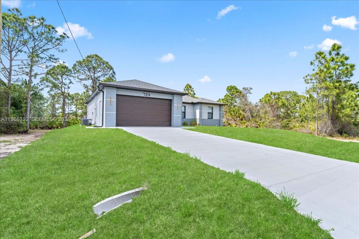 A single-story house with a gray exterior, a two-car garage, and a concrete driveway — 724 Drury Ave, Lehigh Acres FL 33974, LEHIGH ACRES, FL