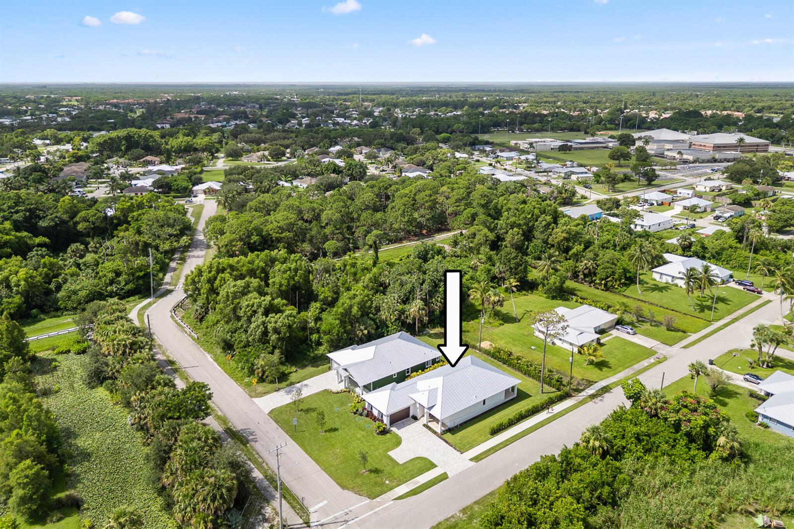 An aerial view shows a modern white house with a metal roof and paved driveway — 5460 SE Front Avenue, Stuart FL 34997, STUART, FL
