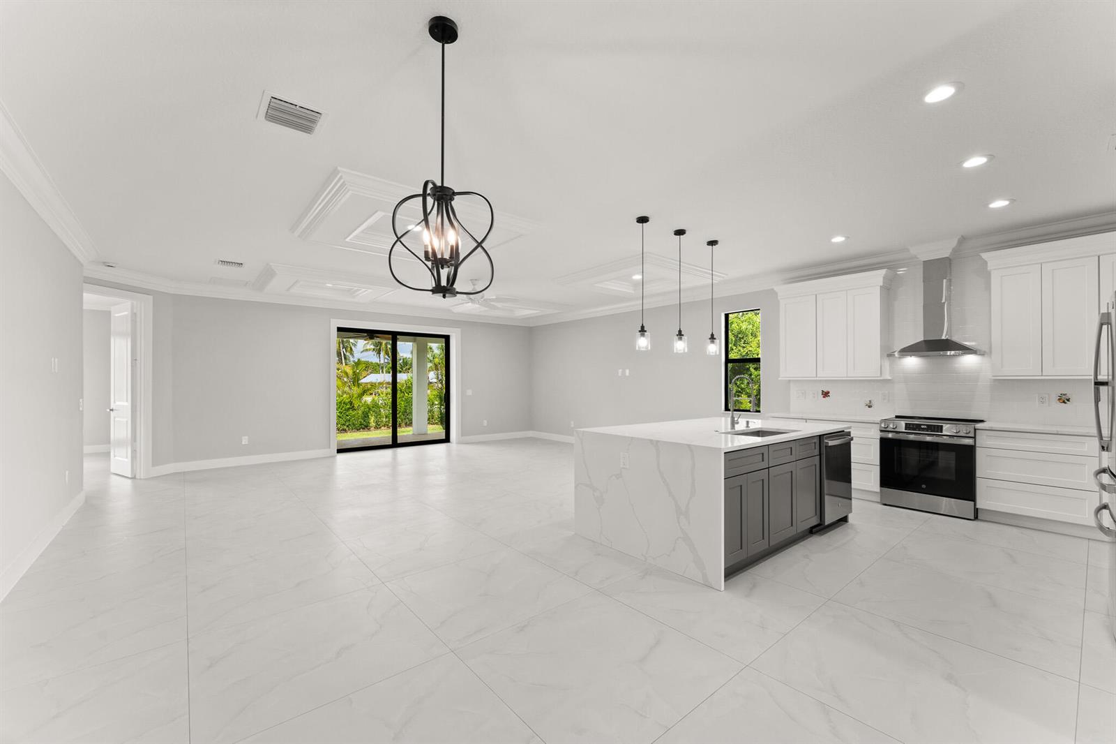 A modern open-concept kitchen and living area with white cabinetry, a gray island, and tile — 5460 SE Front Avenue, Stuart FL 34997, STUART, FL