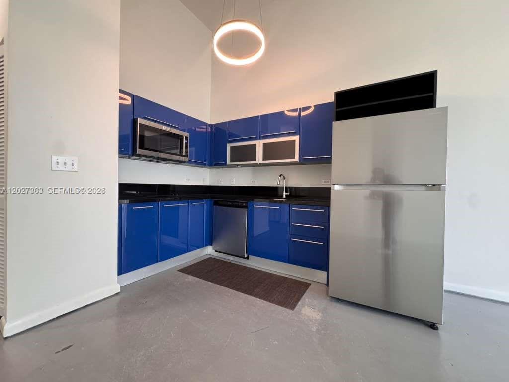 A kitchen features blue high-gloss cabinets, stainless steel appliances, and dark countertops — 253 NE 2nd St # 324, Miami FL 33132, MIAMI, FL