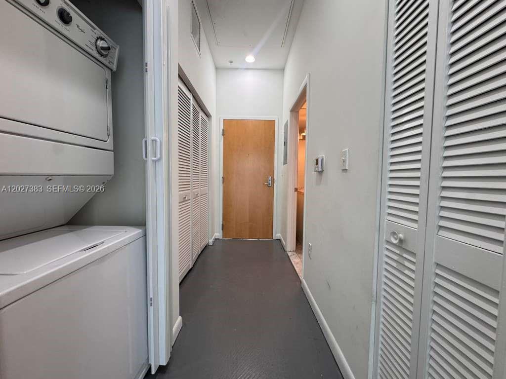 A hallway features a stacked washer and dryer, louvered closet doors, and a wooden door — 253 NE 2nd St # 324, Miami FL 33132, MIAMI, FL