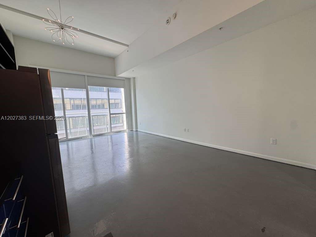 An empty room features gray flooring, white walls, and floor-to-ceiling windows with sliding doors — 253 NE 2nd St # 324, Miami FL 33132, MIAMI, FL