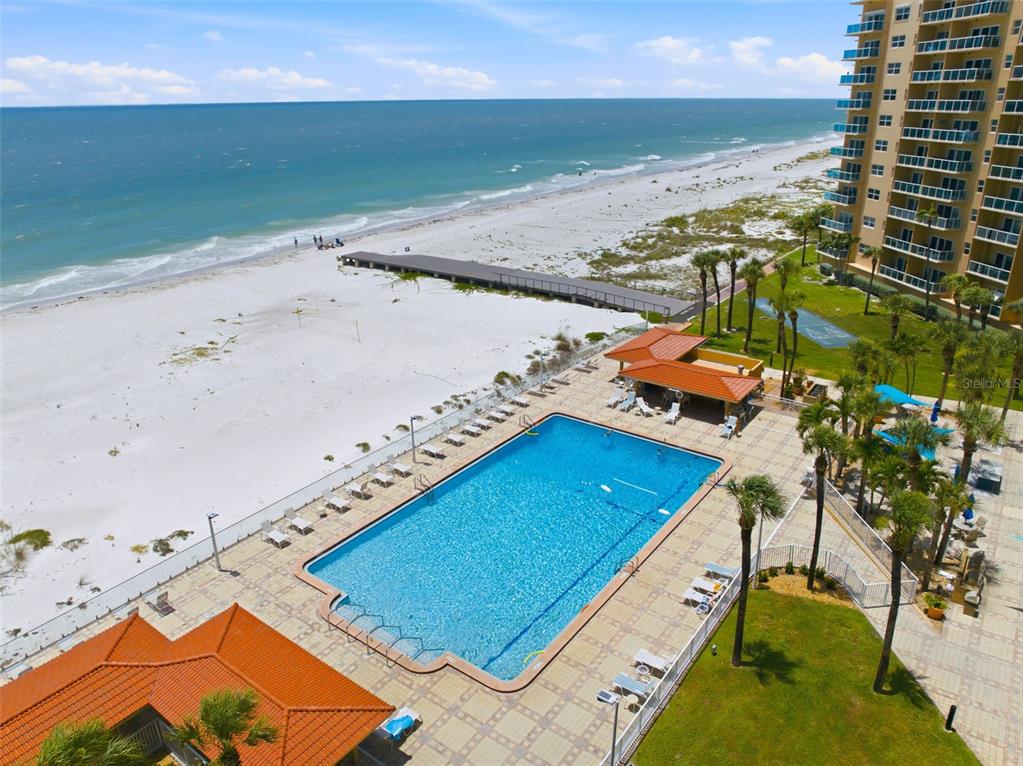 An aerial view shows a rectangular swimming pool, a beach boardwalk, and a high-rise building — 880 MANDALAY AVENUE UNIT C1214, CLEARWATER BEACH, FL