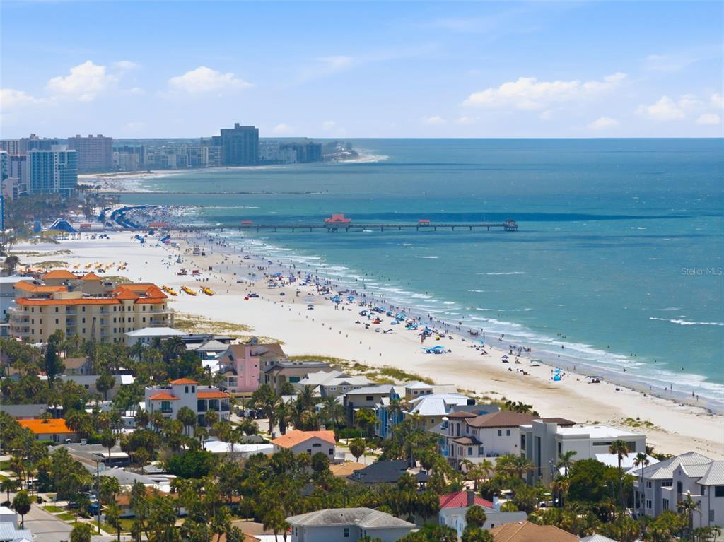 An aerial view of a sandy beach with a long pier and coastal buildings — 880 MANDALAY AVENUE UNIT C1214, CLEARWATER BEACH, FL
