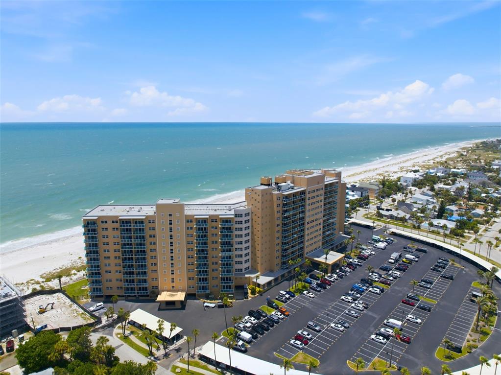 An aerial view shows a large beachfront apartment complex with an adjacent parking lot — 880 MANDALAY AVENUE UNIT C1214, CLEARWATER BEACH, FL