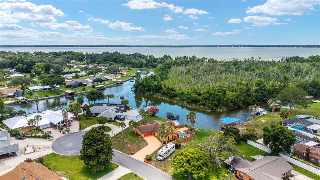 An aerial view shows a residential neighborhood with houses situated along a canal leading to a lake — 5330 KINGS COURT, FRUITLAND PARK, FL