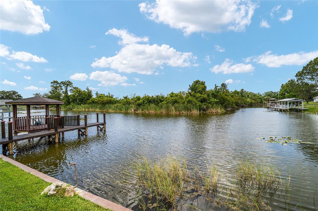 A wooden gazebo and dock sit on a lake surrounded by trees and vegetation — 5330 KINGS COURT, FRUITLAND PARK, FL
