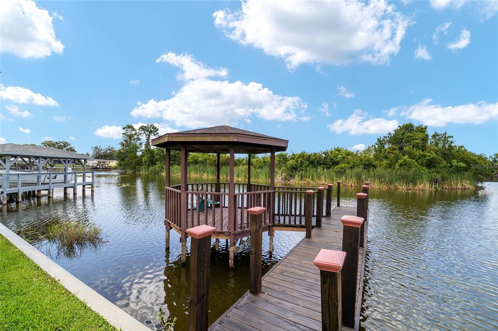 A wooden gazebo sits at the end of a dock extending into a lake — 5330 KINGS COURT, FRUITLAND PARK, FL