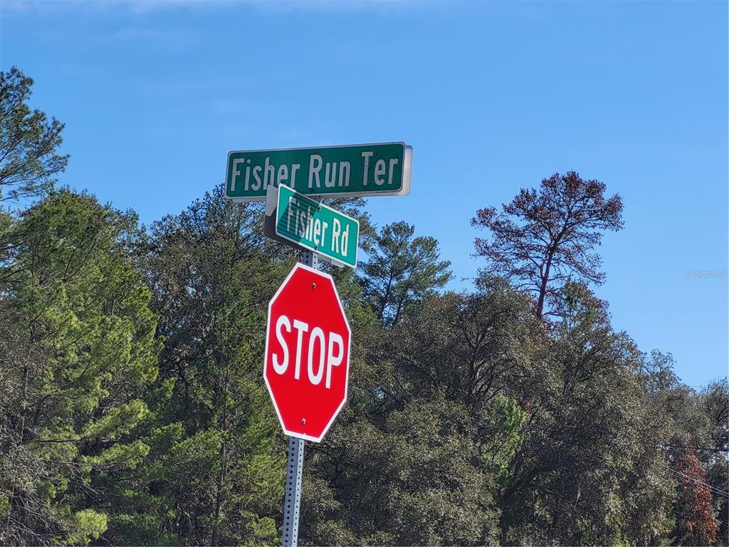 A stop sign stands beneath street signs for Fisher Run Ter and Fisher Rd — TBD SE FISHER RUN TERRACE LOT 15, OCALA, FL