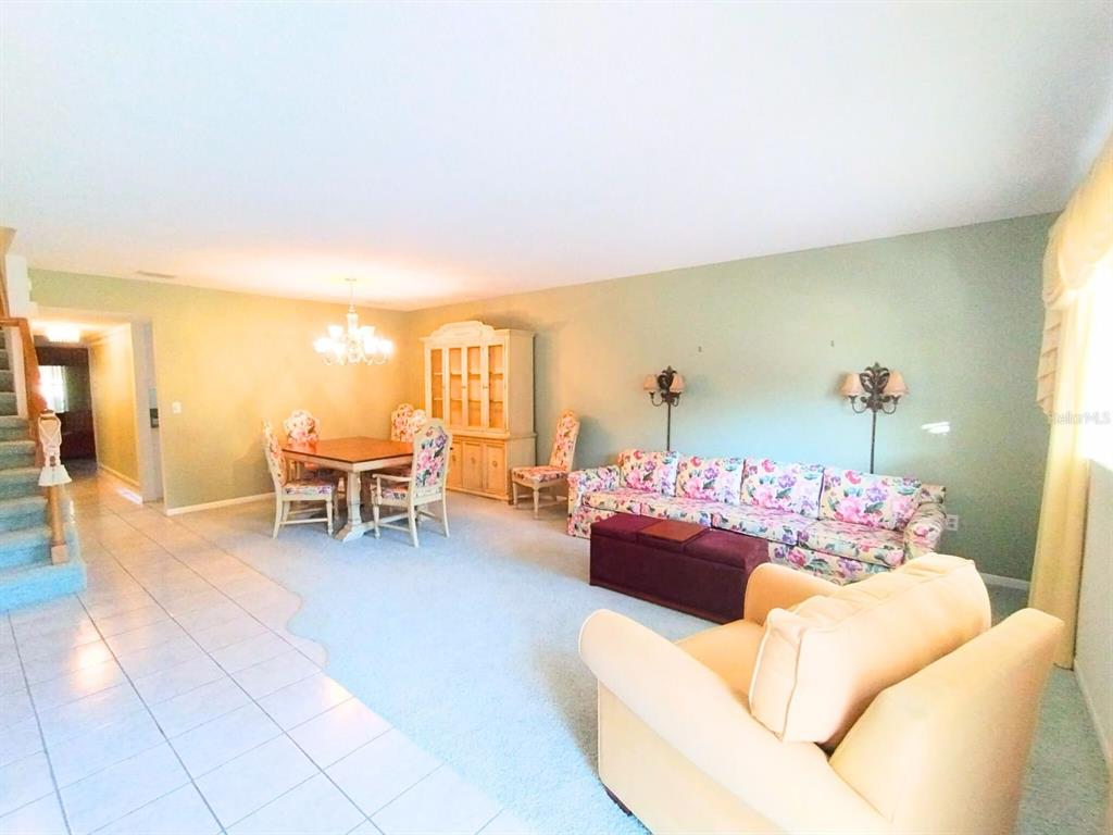 A living and dining area features floral furniture, a hutch, and light-colored carpeting — 8830 SW 98 PLACE UNIT M, OCALA, FL