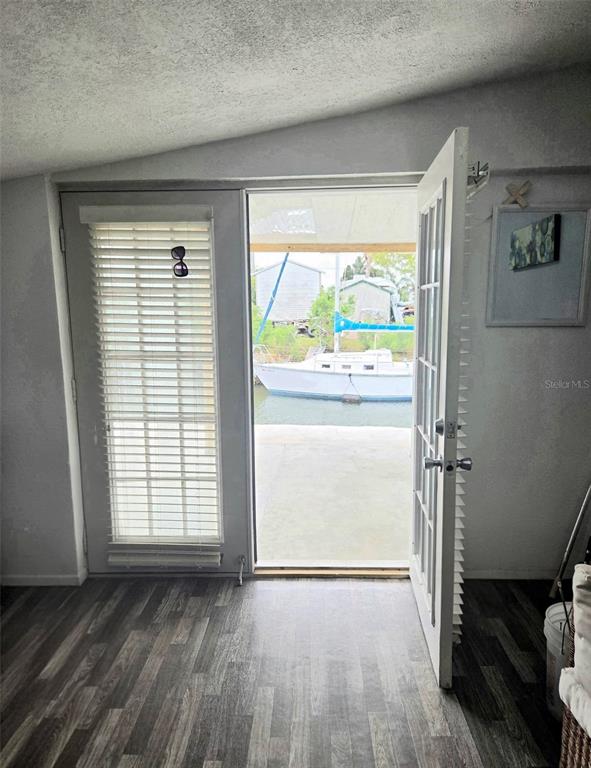 A room with wood-look flooring features a door opening to a boat docked outside — 6726 ALBATROSS LANE, HUDSON, FL