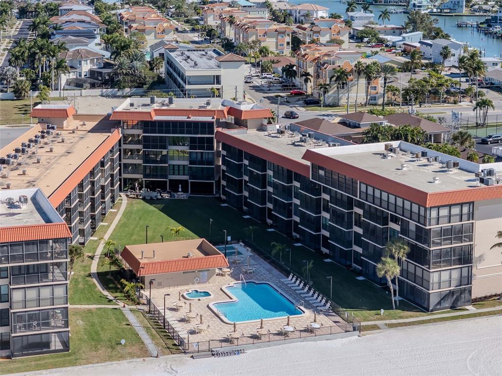 An aerial view shows a multi-story apartment complex with a central pool and courtyard — 17580 GULF BOULEVARD UNIT 403, REDINGTON SHORES, FL