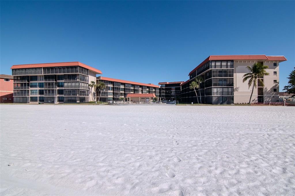 A multi-story beachfront condominium complex with a white sand beach in the foreground — 17580 GULF BOULEVARD UNIT 403, REDINGTON SHORES, FL