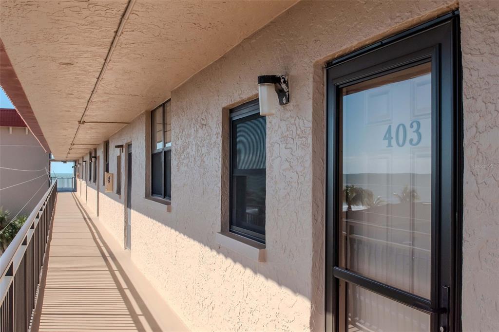 An exterior walkway leads past several apartment doors with unit 403 in the foreground — 17580 GULF BOULEVARD UNIT 403, REDINGTON SHORES, FL