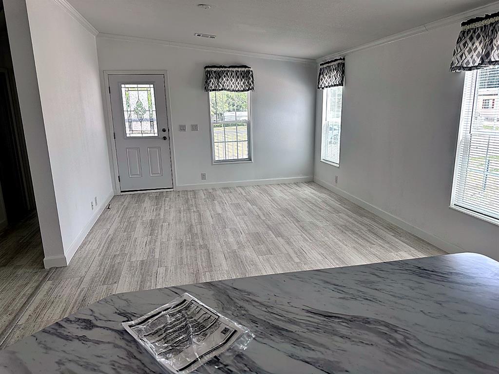 A living room with light wood-look flooring, white walls, and a front door with glass — 3492 GREENBLUFF ROAD UNIT 1119, ZELLWOOD, FL