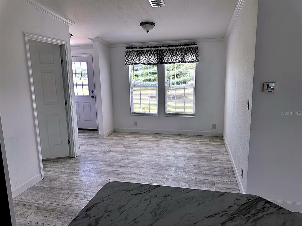 A room with light wood-look tile flooring, white walls, two windows, and a door — 3492 GREENBLUFF ROAD UNIT 1119, ZELLWOOD, FL