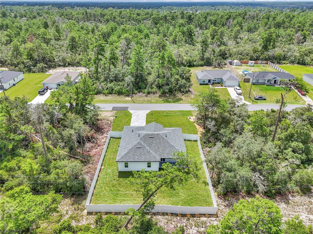 An aerial view shows a house with a fenced backyard surrounded by dense forest — 17226 SW 20TH COURT ROAD, OCALA, FL