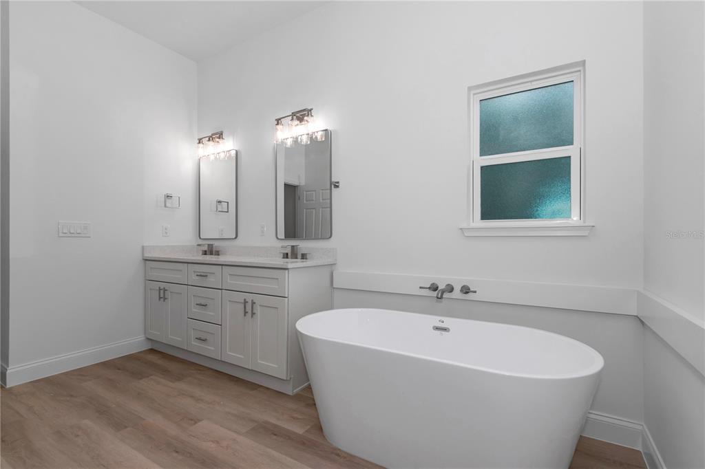 A bathroom features a double vanity, a freestanding white bathtub, and light wood-look flooring — 17226 SW 20TH COURT ROAD, OCALA, FL