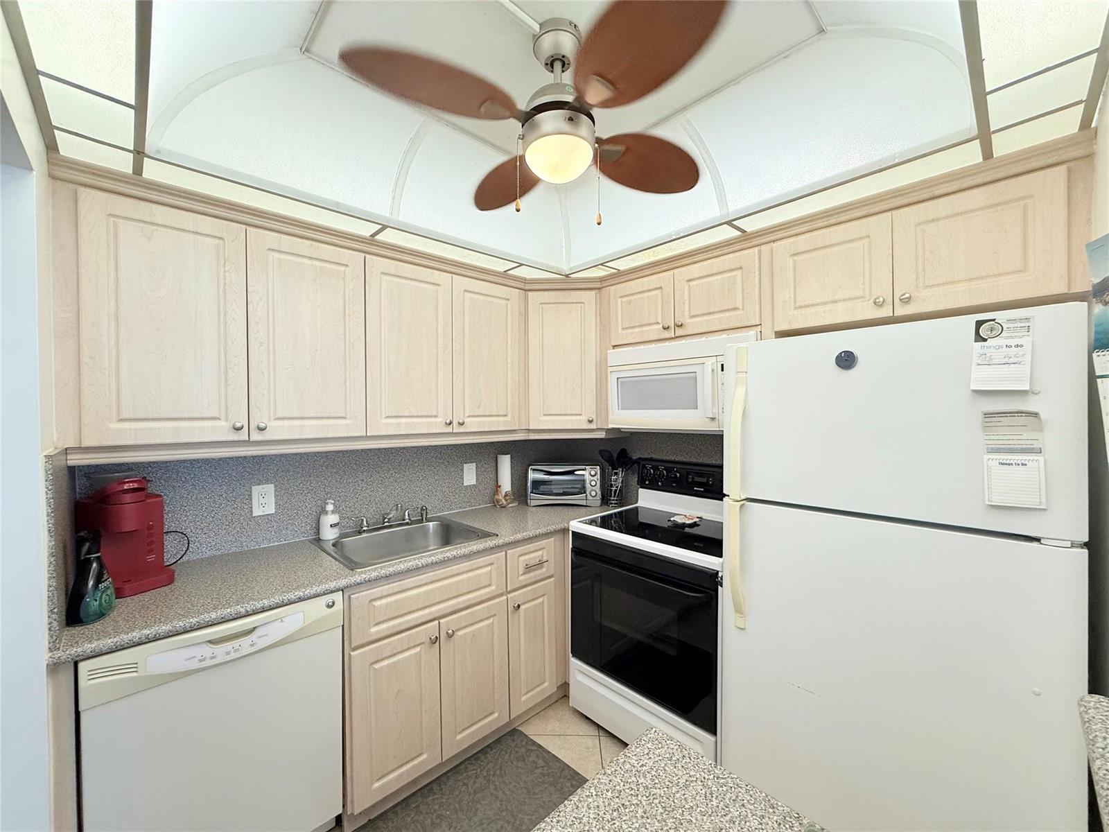 A kitchen with light wood cabinets, speckled countertops, white appliances, and a ceiling fan — 53 Markham C # 53, Deerfield Beach FL 33442, DEERFIELD BEACH, FL