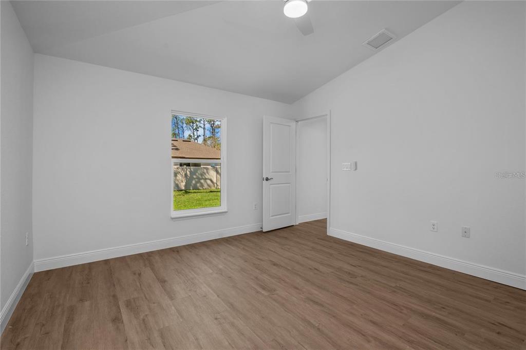 An empty bedroom features white walls, wood-look flooring, a ceiling fan, and a window — 4442 ANTIOCH STREET, NORTH PORT, FL