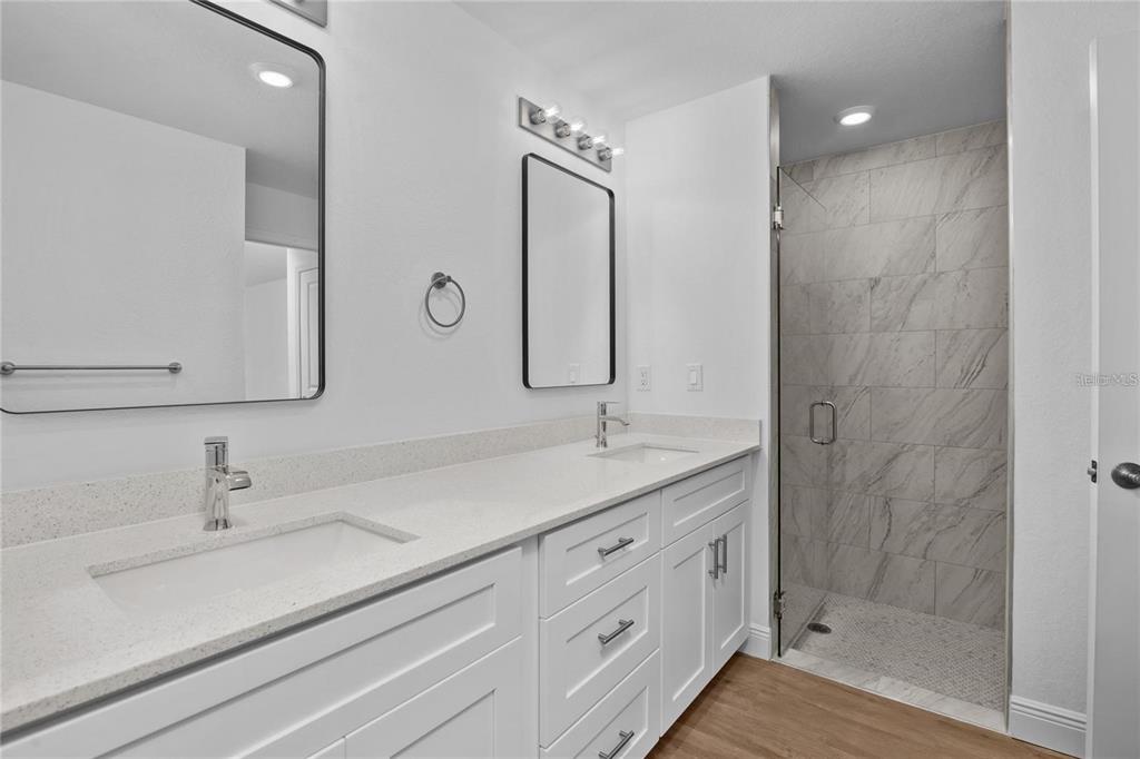 A modern bathroom features a double vanity with white cabinets and a walk-in tiled shower — 4442 ANTIOCH STREET, NORTH PORT, FL