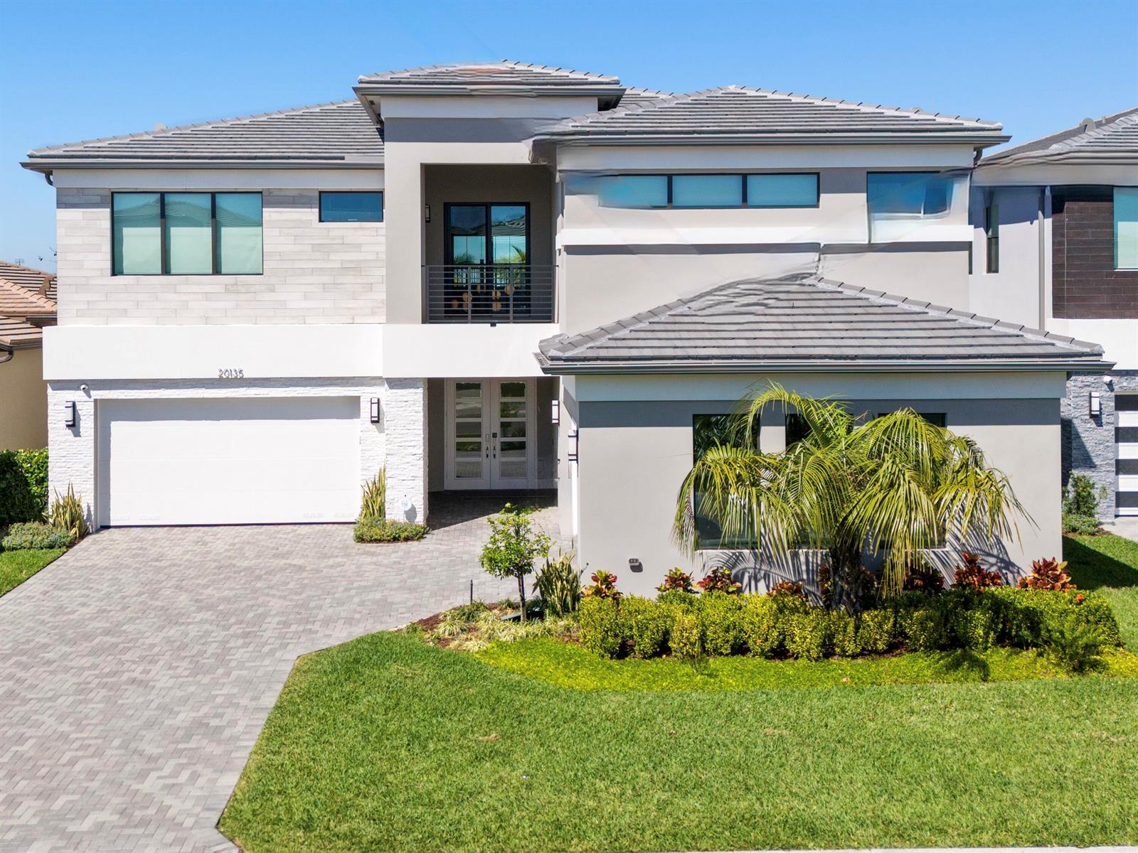 A two-story modern house features a gray tiled roof, white stone accents, and a paved driveway — 20135 Casa De Campo Lane, Boca Raton FL 33434, BOCA RATON, FL