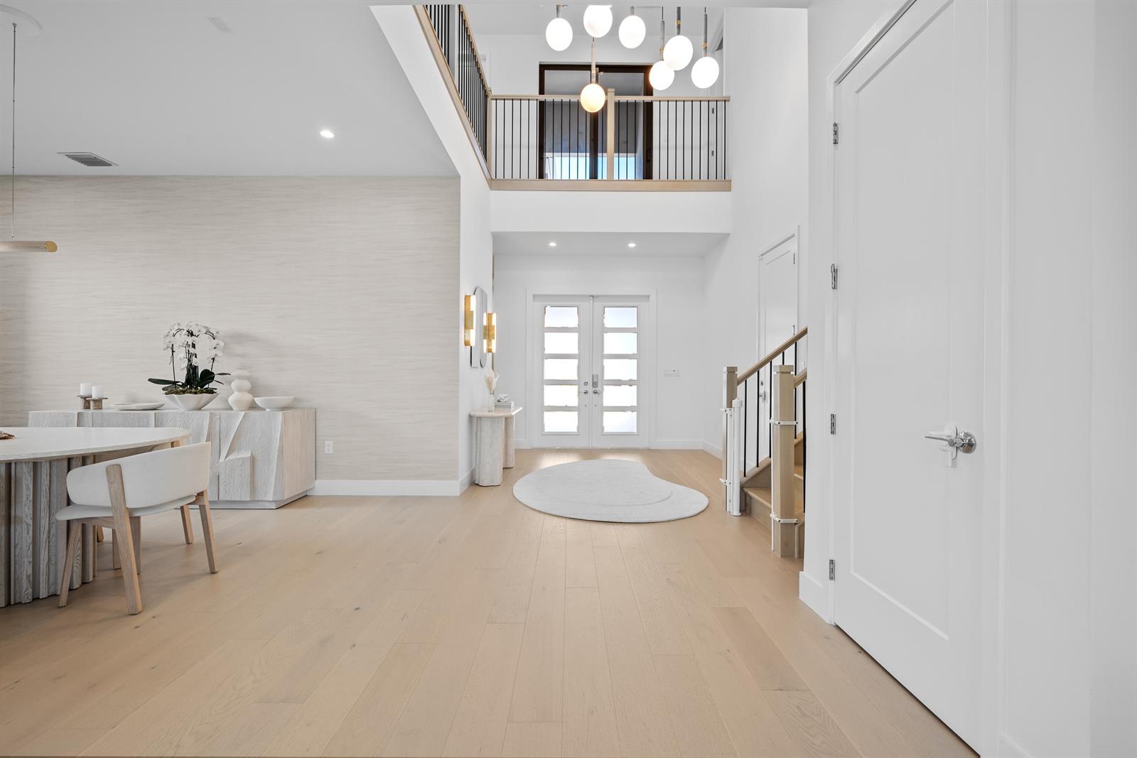 A bright foyer features light wood flooring, a double-door entrance, and a modern chandelier — 20135 Casa De Campo Lane, Boca Raton FL 33434, BOCA RATON, FL