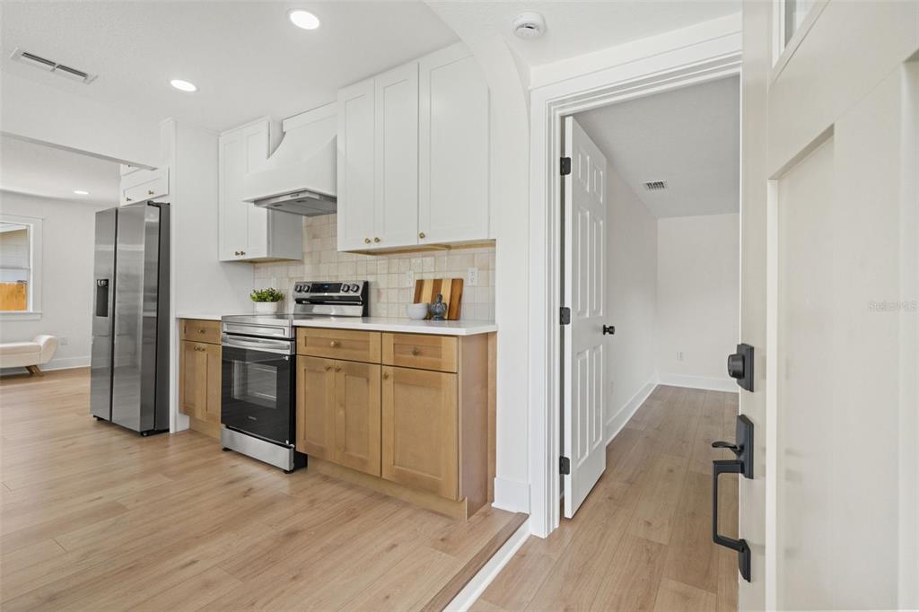 A kitchen features light wood lower cabinets, white upper cabinets, and stainless steel appliances — 3036 20TH STREET N, ST PETERSBURG, FL