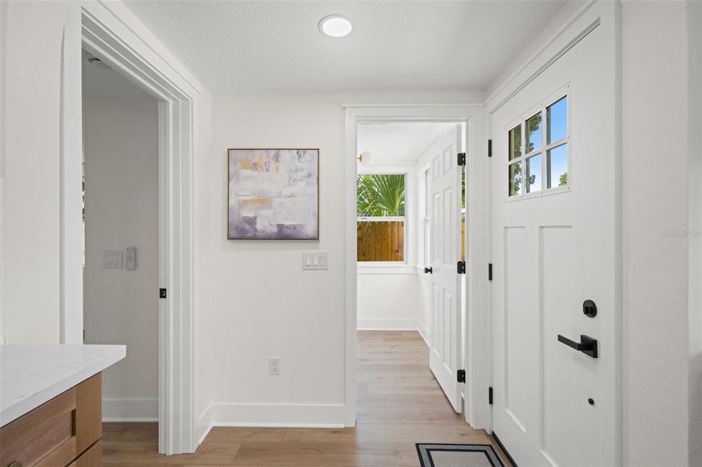 A bright entryway features white walls, light wood flooring, and a white front door — 3036 20TH STREET N, ST PETERSBURG, FL
