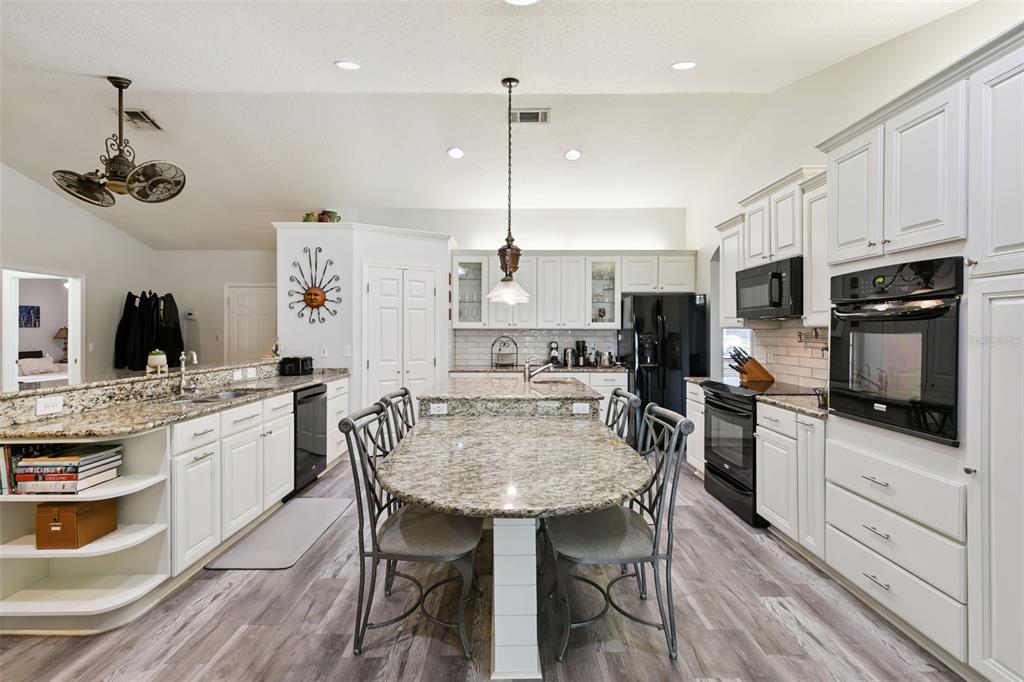 A kitchen features white cabinets, granite countertops, a central island, and black appliances — 1209 DEER RUN DRIVE, WINTER SPRINGS, FL