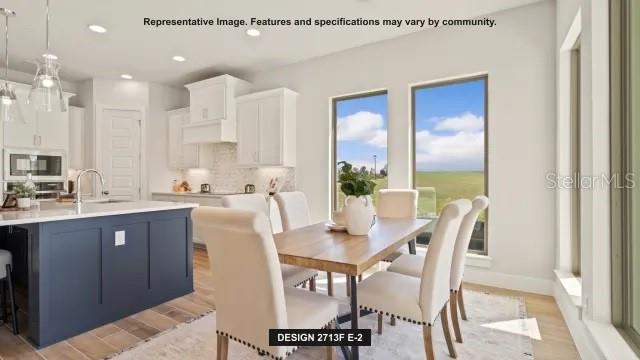 A kitchen with a blue island and a dining area featuring large windows and chairs — 294 HOLLY BANK AVENUE, NOKOMIS, FL