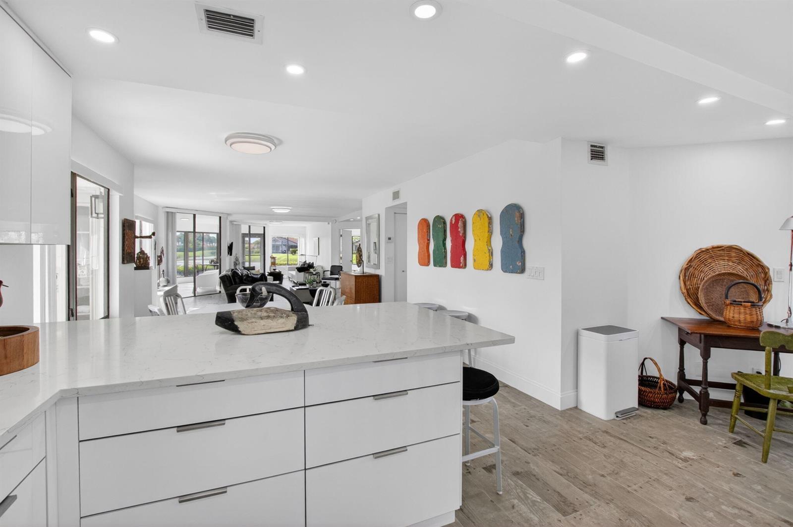 A white kitchen island with quartz countertops sits in an open-concept living space — 15354 Strathearn Drive # 12601, Delray Beach FL 33446, DELRAY BEACH, FL