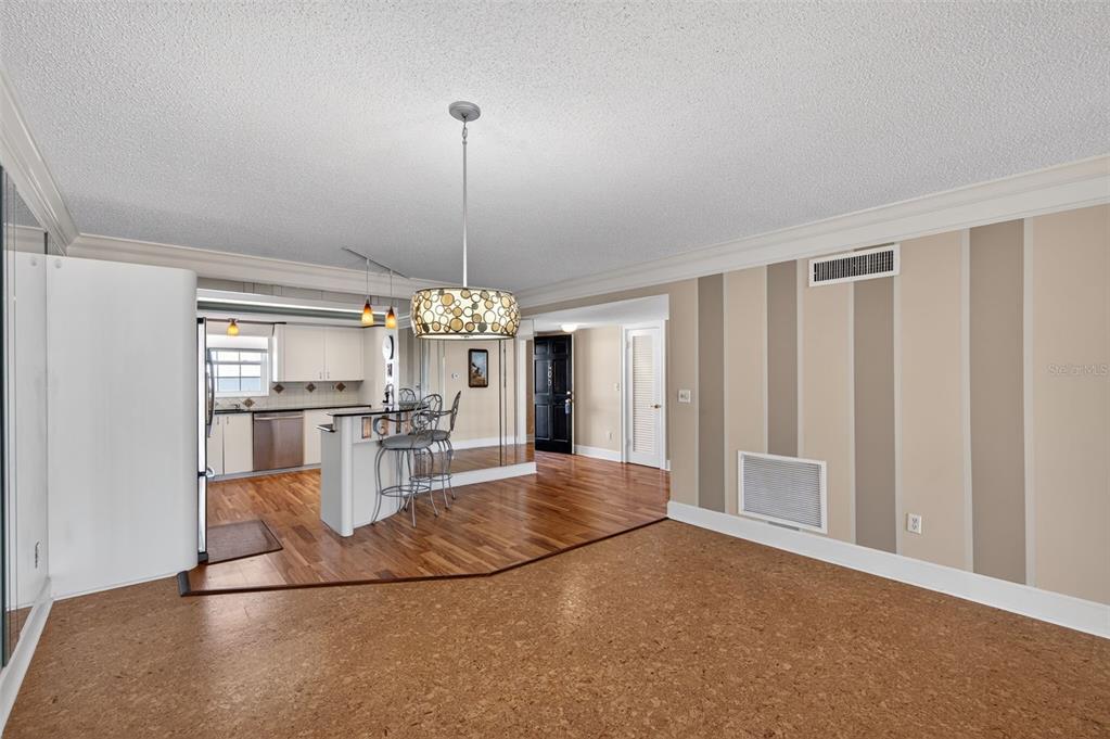 A dining area with a wooden table and gray chairs sits before a mirrored wall — 131 BLUFF VIEW DRIVE UNIT 403, BELLEAIR BLUFFS, FL