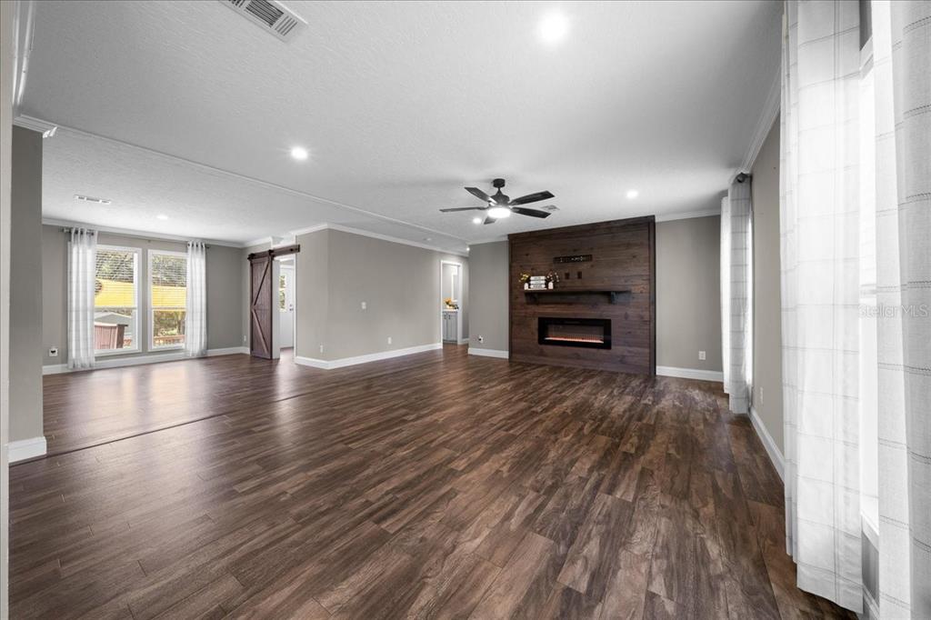 A spacious living room features wood-look flooring, a dark wood fireplace accent wall, and recessed lighting — 14450 SE SUNSET HARBOR ROAD, WEIRSDALE, FL