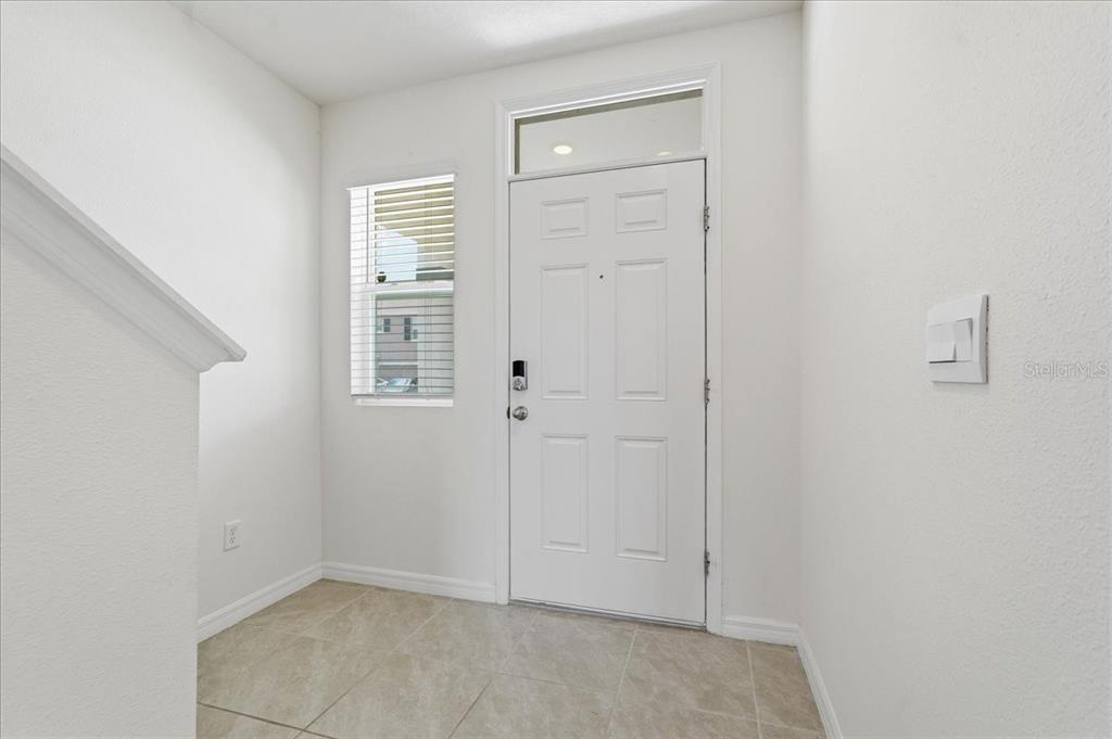 An entryway features a white front door, a side window, and light-colored tile flooring — 33503 ELM HILL BRANCH, WESLEY CHAPEL, FL