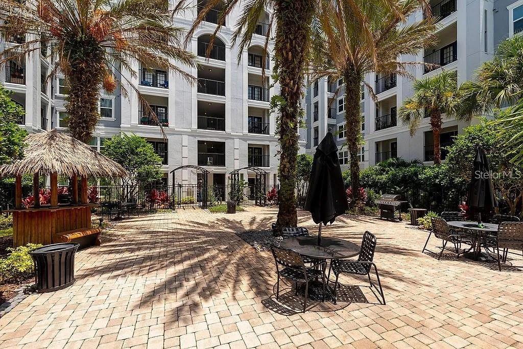 A paved courtyard features palm trees, outdoor seating, and a tiki-style bar area — 204 SOUTH STREET UNIT 1053, ORLANDO, FL