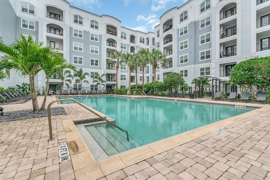 A swimming pool with a shallow entry area sits in a courtyard between apartment buildings — 204 SOUTH STREET UNIT 1053, ORLANDO, FL