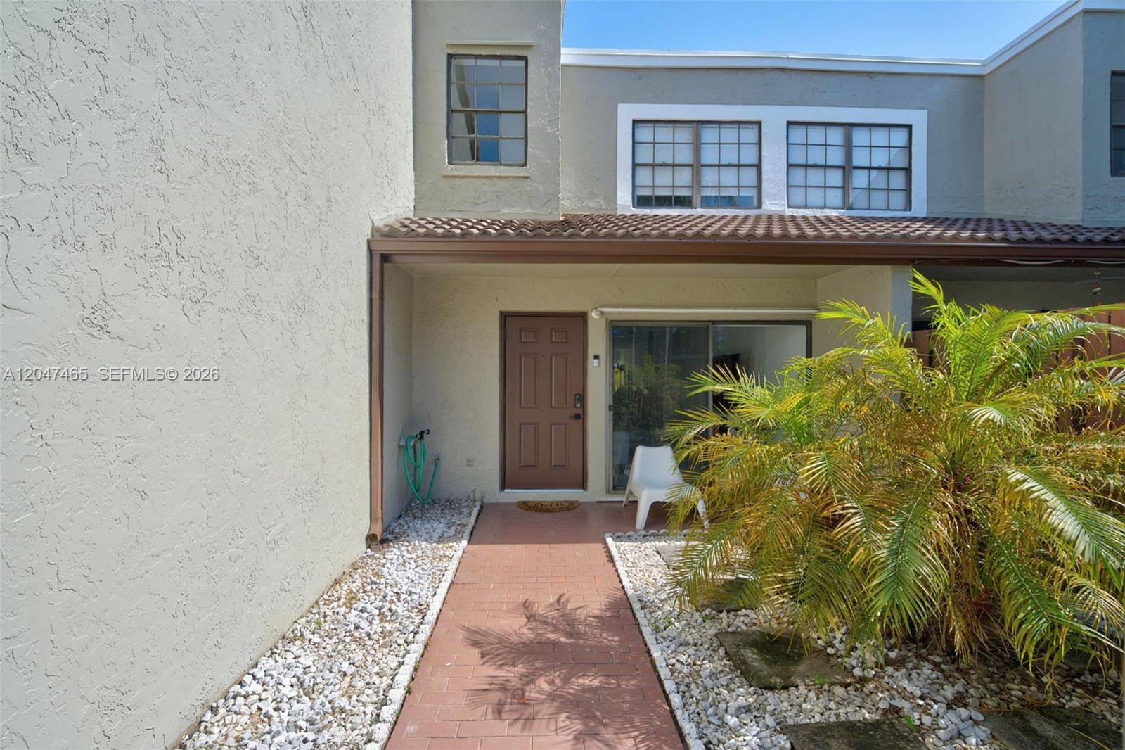 A brown front door and sliding glass door are accessible via a brick walkway — 10505 SW 153rd Ct # 7, Miami FL 33196, MIAMI, FL