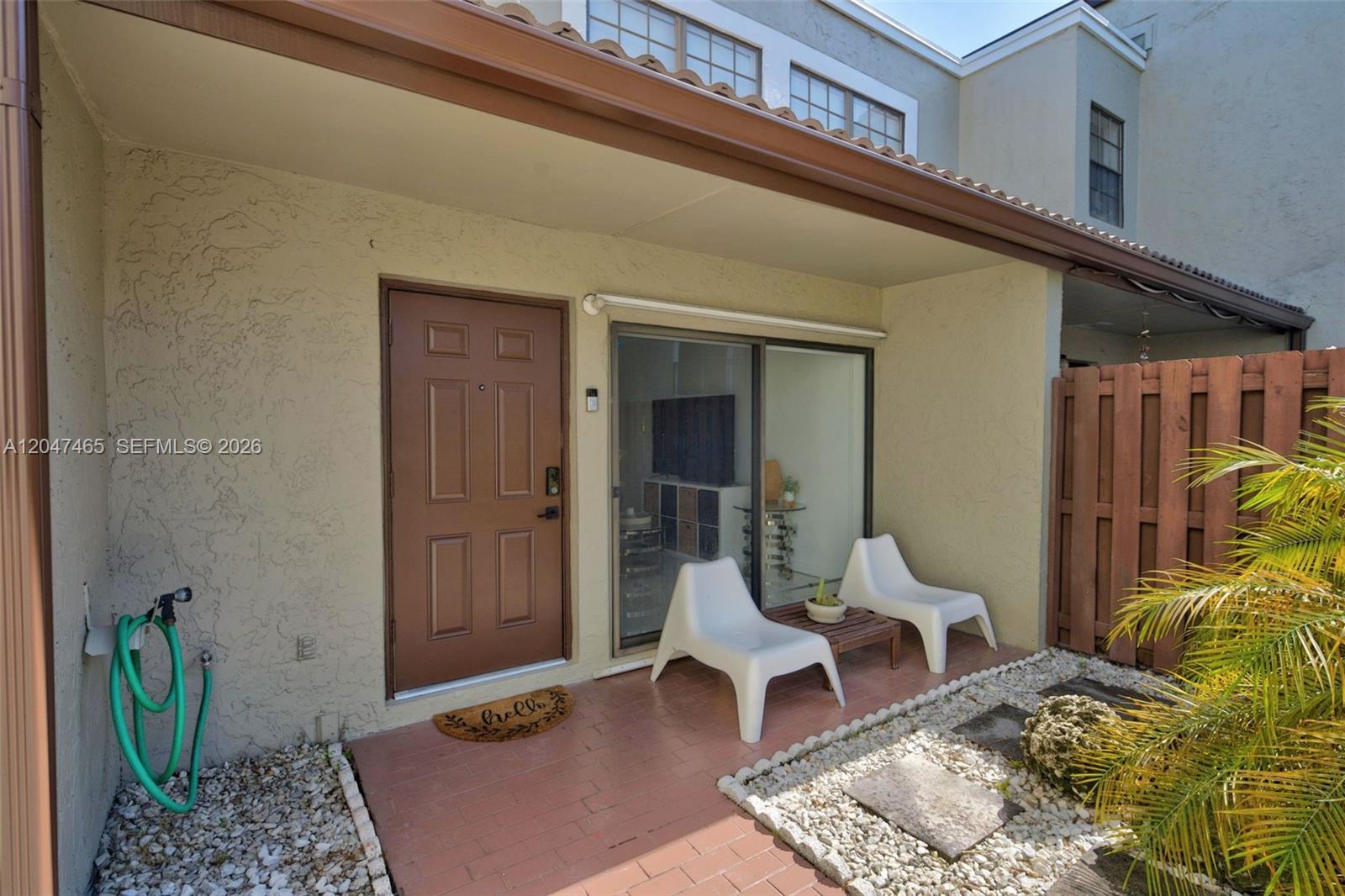A patio features a brown door, sliding glass doors, two white chairs, and a hose — 10505 SW 153rd Ct # 7, Miami FL 33196, MIAMI, FL